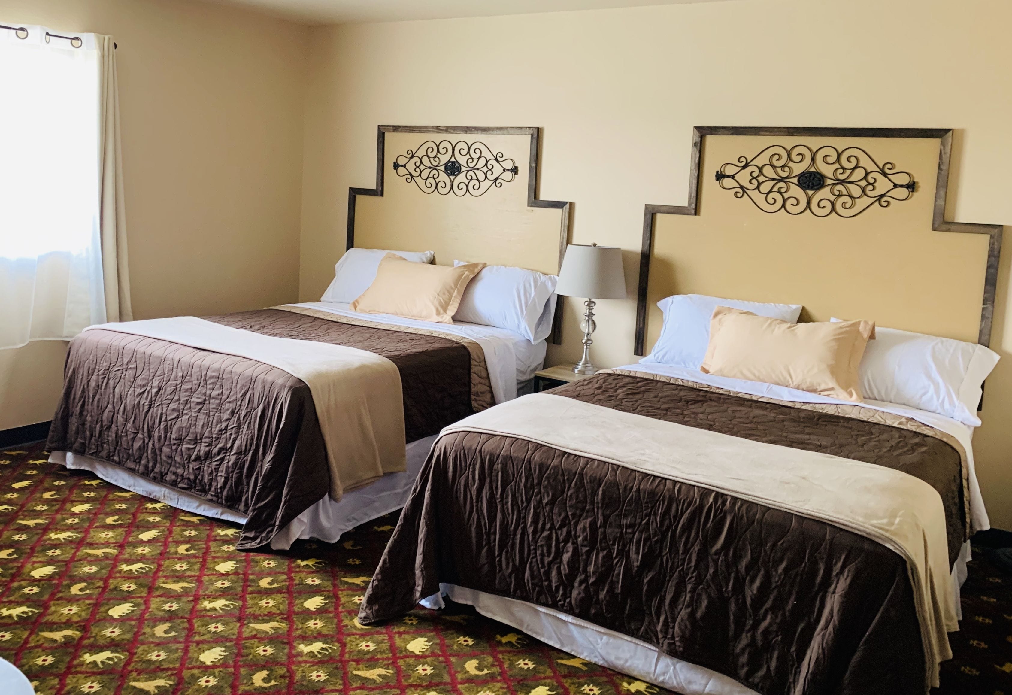 Two double beds with headboards, a patterned carpet, and a window with curtains.