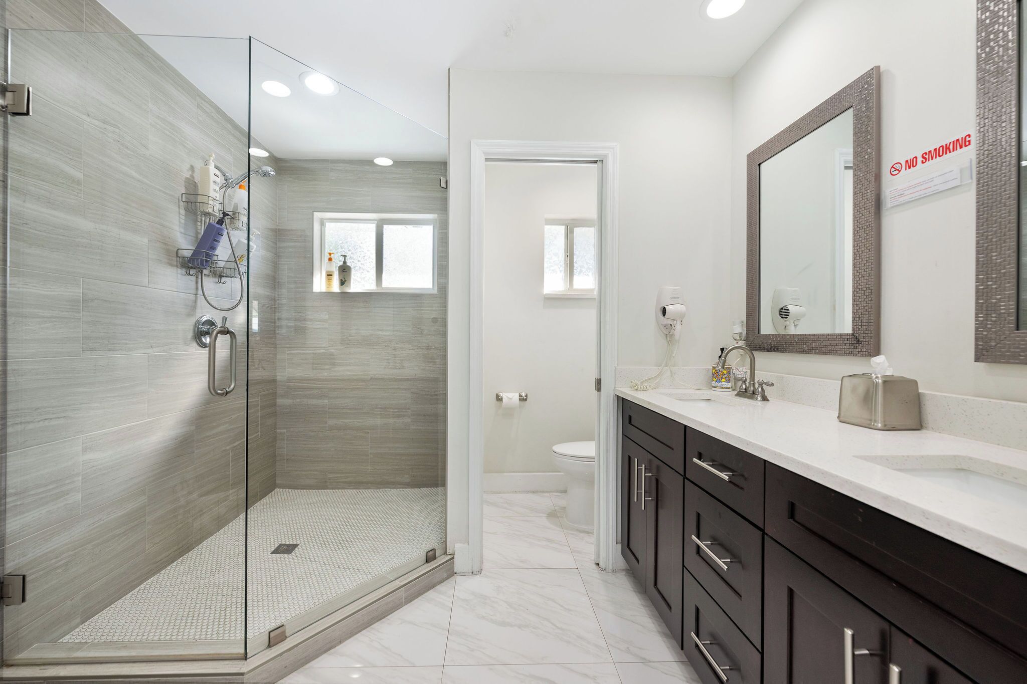 Une salle de bain moderne avec une douche à parois de verre, un lavabo avec un miroir et des toilettes.