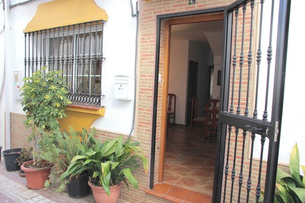 A building entrance with a metal gate, potted plants, and a yellow awning. - RDR164 - Townhouse Marbella Centre (Marbella)