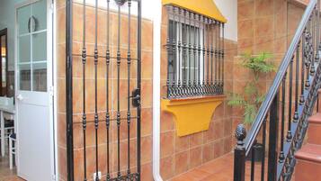 Un escalier avec une rampe en métal, une porte avec un panneau de verre et un mur recouvert de carreaux.