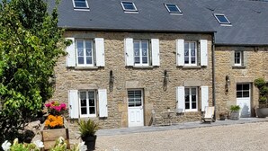 A stone building with multiple windows and shutters, a gravel driveway, and outdoor seating. - Beautiful renovated house - 3 Bedrooms - Sea & Countryside (Maupertus-sur-Mer)