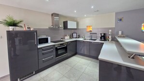 A modern kitchen with a refrigerator, microwave, oven, sink, and a countertop with a coffee maker. - Beautiful renovated house - 3 Bedrooms - Sea & Countryside (Maupertus-sur-Mer)
