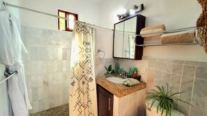 A bathroom with a shower curtain, a sink with a mirror above it, and a towel rack.