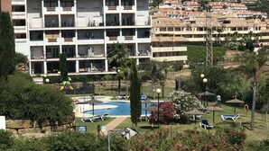 A hotel with multiple balconies, a swimming pool, and lush greenery. - Manilva Playa luxury apartment with sea view near the beach (Manilva)