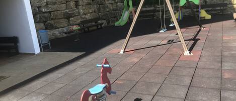 Une aire de jeux avec des balançoires et un toboggan.