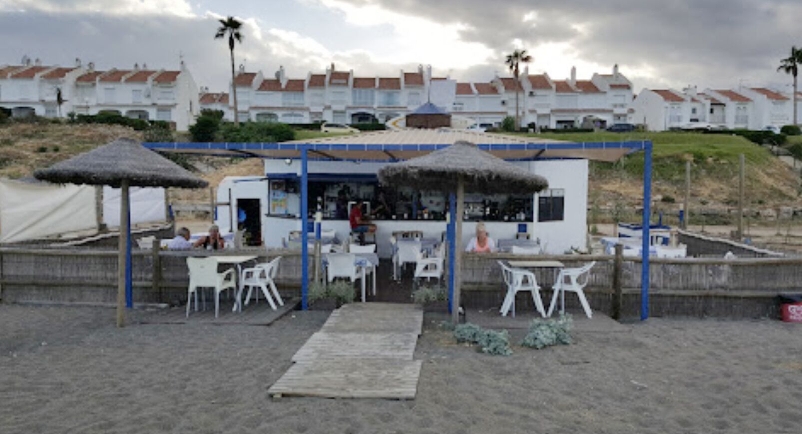 Ein Café direkt am Strand mit Außenbereich und einem strohgedeckten Dach.