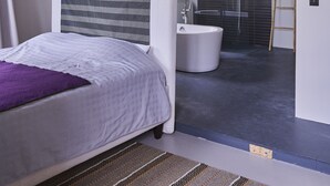 Un dormitorio moderno con una cama grande, un vestidor, una bañera y una ducha.