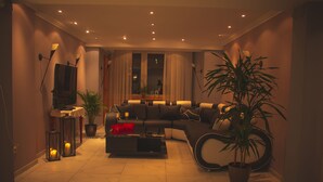 A modern living room with a sectional sofa, a coffee table, and a potted plant. - Hotel Alpenrose (Bad Woerishofen)