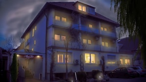 A multi-story residential building with a staircase leading to the entrance, a balcony on the second floor, and a parked car in the driveway. - Hotel Alpenrose (Bad Woerishofen)