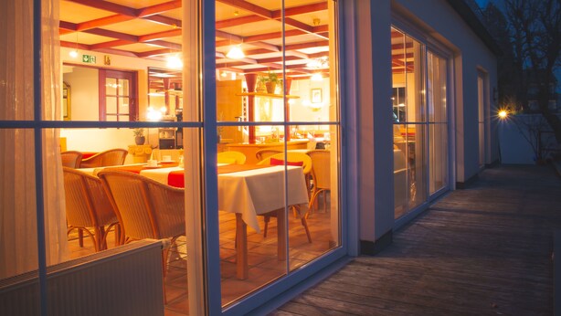 A restaurant with a wooden deck and large glass windows. - Hotel Alpenrose (Bad Woerishofen)