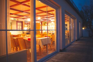 A restaurant with a wooden deck and large glass windows. - Hotel Alpenrose (Bad Woerishofen)
