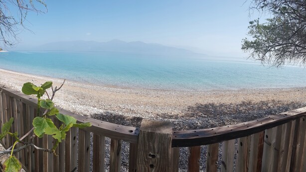 Una recinzione di legno con vista su una spiaggia e montagne sullo sfondo.