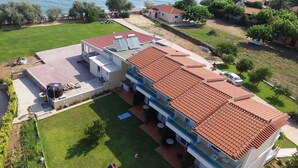Una moderna casa a due piani con tetto in tegole rosse, una piscina e vista mare.