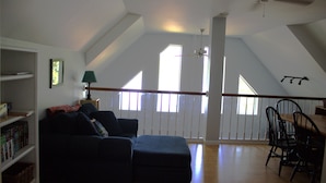 Ein Loft-Zimmer mit einem dunkelblauen Sofa, einem Esstisch mit Stühlen und einem Deckenventilator.
