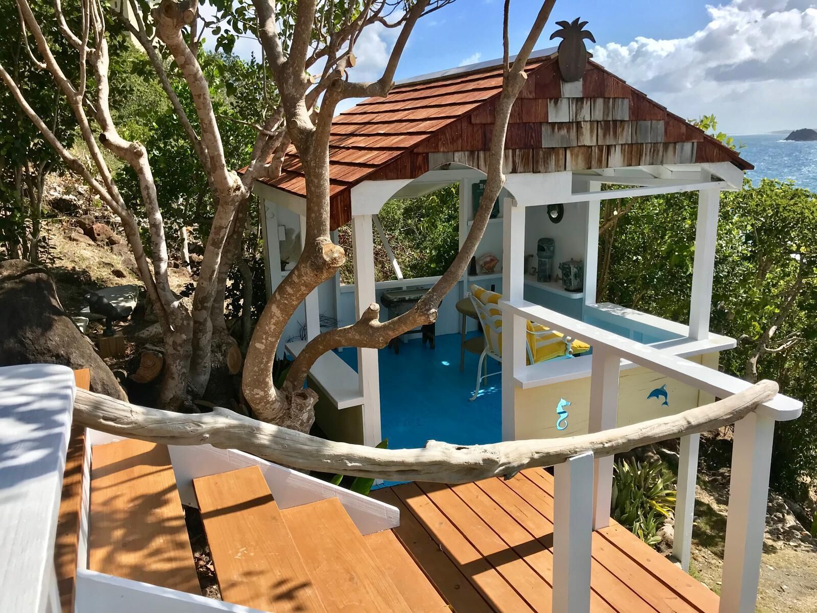 A wooden deck with a pool, surrounded by trees and a view of the ocean.