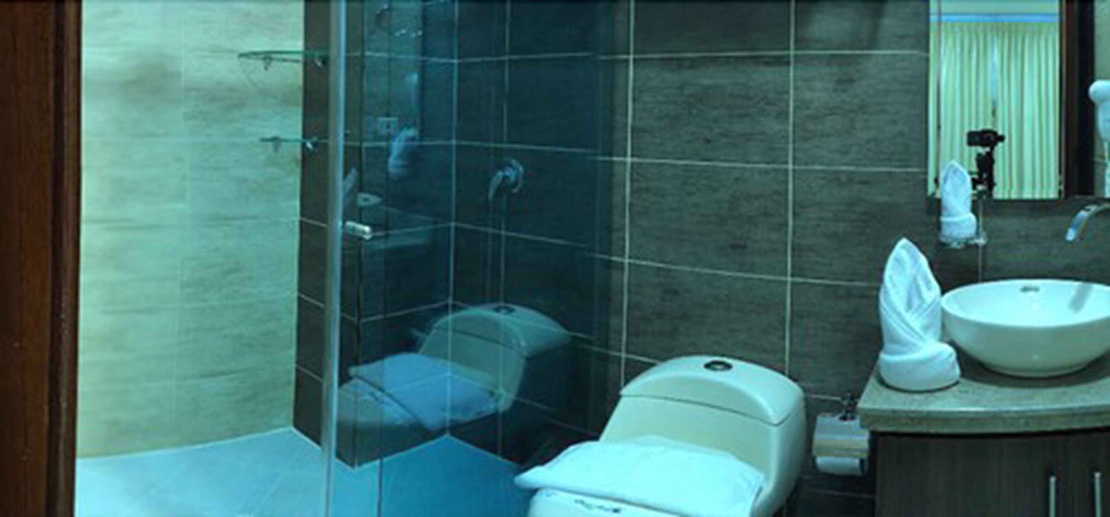 Un baño moderno con cabina de ducha de vidrio, inodoro y lavamanos con espejo.
