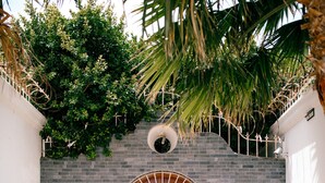 Une entrée fermée par un portail, avec un chemin dallé menant à un bâtiment doté d’un mur en briques et d’une porte en bois.