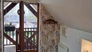 Un interior moderno con una escalera de madera que lleva a un balcón, un muro con diseño y un tarro de vidrio con piedras sobre una estantería.