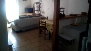 Ein Zimmer mit einem Bett, einem Esstisch mit Stühlen, einem Fernseher und einem dekorativen Käfig.