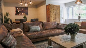 Una sala de estar con un sofá modular, una mesa de centro de madera y un comedor con una mesa y sillas.