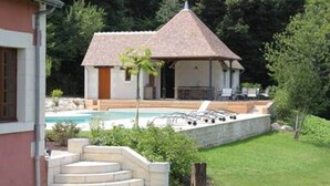 Una casa con piscina, un espacio exterior cubierto y una escalera que lleva a la casa.
