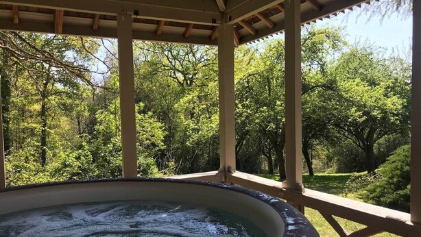Un jacuzzi en un espacio exterior cubierto con vistas a un bosque verde y frondoso.