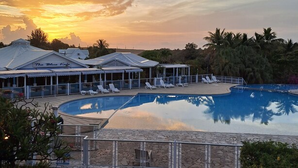 A resort with a swimming pool, lounge chairs, and a covered area with umbrellas.