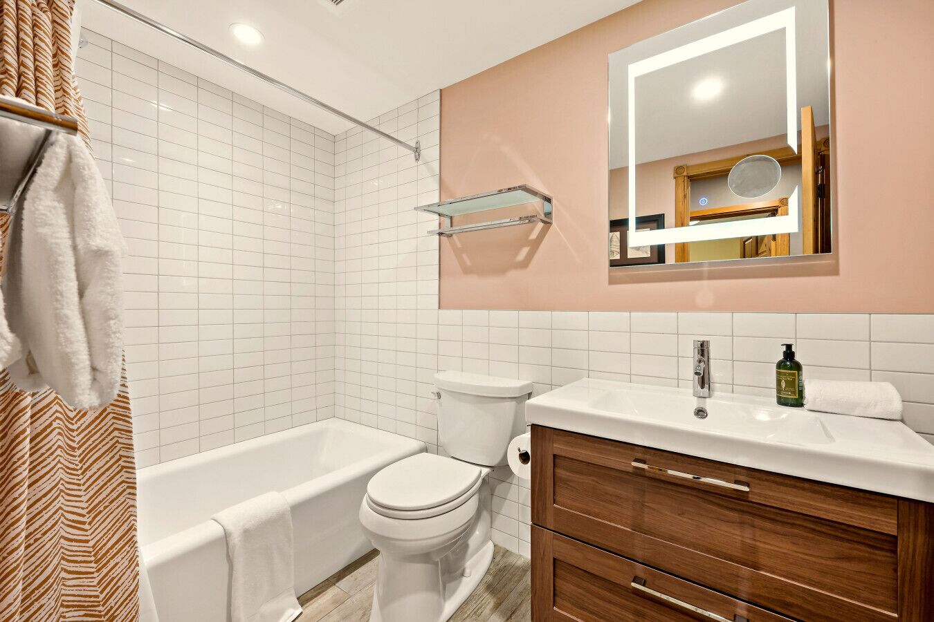 Un baño moderno con una bañera blanca, un inodoro y un tocador con espejo.