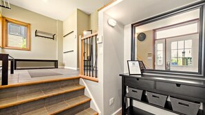 A staircase with wooden steps and a black railing, leading to a landing with a black console and baskets.