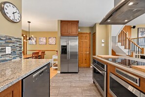 A modern kitchen with a stainless steel refrigerator, built-in oven, and granite countertops. - Tremblant Prestige - Clairiere 406 (Mont-Tremblant)