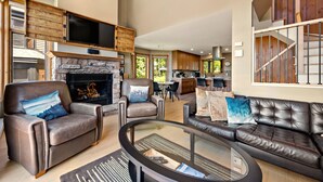 A spacious living area with leather sofas, a fireplace, and a kitchen in the background.