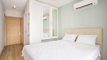 A bedroom with a bed, wardrobe, and an air conditioning unit.