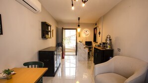 A modern living room with a sofa, a dining table with chairs, and a kitchen area with a marble countertop. - Pharos Hotel (Datça)