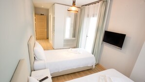 A hotel room with two beds, a TV, a desk, and a bathroom visible through an open door. - Pharos Hotel (Datça)