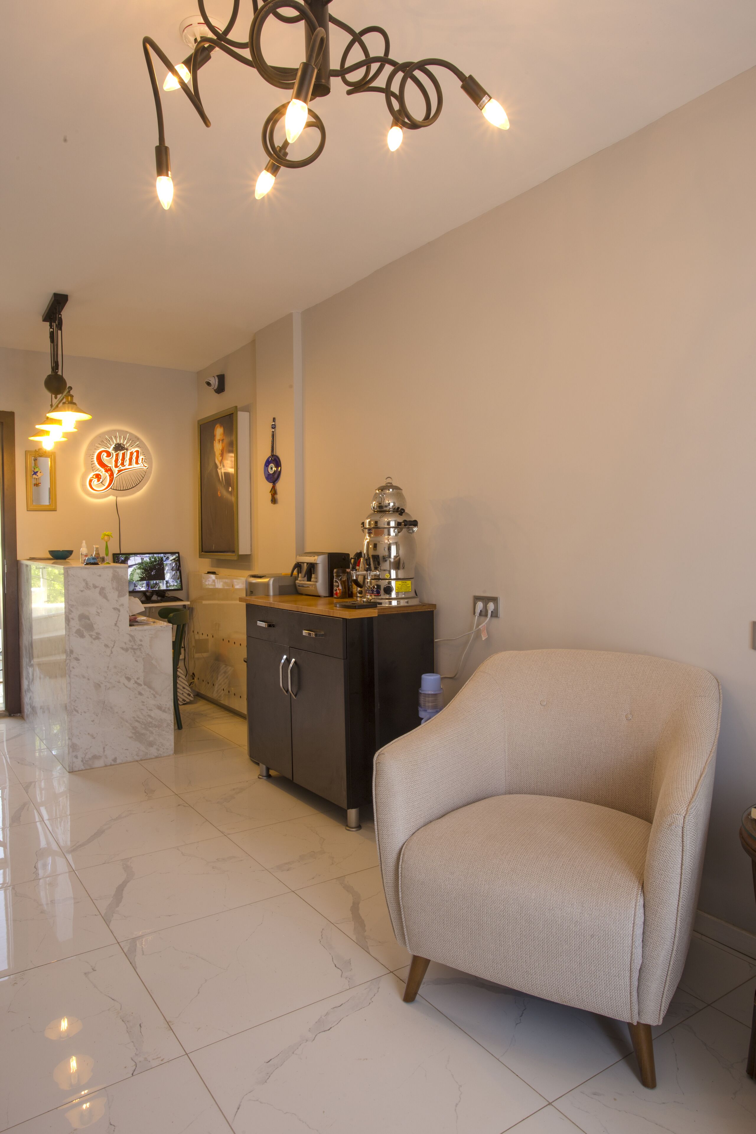 A modern kitchen with a marble countertop, a coffee machine, and a neon sign.