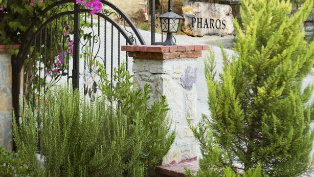 A wrought iron gate with a stone plaque reading "PHAROS" and a sign above it. - Pharos Hotel (Datça)