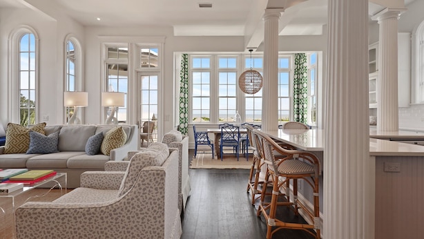 A spacious living room with a sofa, chairs, and a dining area with a table and chairs. - Spectacular Ocean Views! Immaculate Family Oceanfront Home, Pool, Rooftop Deck! Emmeline Cottage (Saint Simons Island)