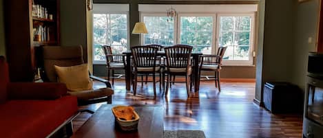 Un salon spacieux avec un canapé rouge, une table basse en bois et un coin repas comprenant des chaises et une table en bois.