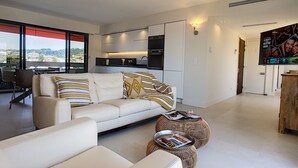 A modern living room with a sofa, ottoman, and a dining area with chairs.