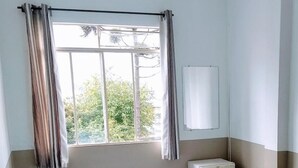 A room with a bed, a window with curtains, a bedside table, and a ceiling light. - Hotel Aruba (Curitiba)