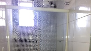 A bathroom with a tiled shower enclosure, a toilet, and a sink with a dark countertop. - Hotel Aruba (Curitiba)