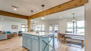 A spacious kitchen with a large island, wooden beams, and pendant lighting. - Life is Better at the Lake. Come relax at FishCamp@PK (Graford)