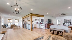 A spacious living room with a large wooden dining table, wicker furniture, and a television. - Life is Better at the Lake. Come relax at FishCamp@PK (Graford)