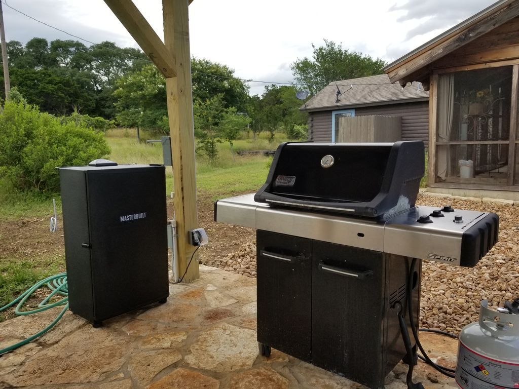 Un espacio de cocina al aire libre con una parrilla, un refrigerador integrado y un tanque de propano.