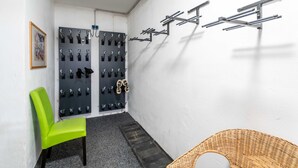 A small room with a green chair, a wall-mounted shoe rack, and a wicker basket. - Living Eden - TOP 3, city center & balcony (Zell am See)