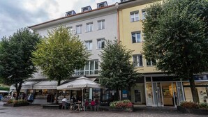 A building with multiple storefronts, including a clothing store and a restaurant. - Living Eden - TOP 3, city center & balcony (Zell am See)