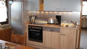 A compact kitchen with a refrigerator, stove, dishwasher, and a coffee maker on the countertop. - Many excursion destinations, e.g. Museumsdorf, wildlife park, Altes Land, opera, theater and musical. (Hamburg)