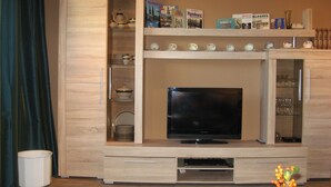 A living room with a TV, wooden cabinets, and a bookshelf with books. - Many excursion destinations, e.g. Museumsdorf, wildlife park, Altes Land, opera, theater and musical. (Hamburg)