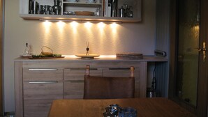 A kitchen with wooden cabinets, a dining table, and various kitchenware on open shelves. - Many excursion destinations, e.g. Museumsdorf, wildlife park, Altes Land, opera, theater and musical. (Hamburg)