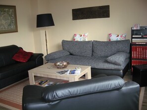 A living room with a grey sofa, a black leather couch, a wooden coffee table, and a floor lamp. - Many excursion destinations, e.g. Museumsdorf, wildlife park, Altes Land, opera, theater and musical. (Hamburg)